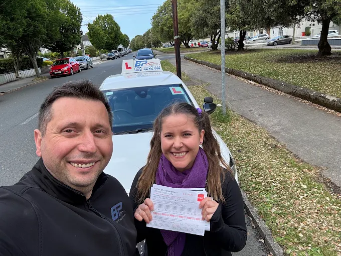 Student holding RSA driving test pass certificate next to BP Driving School Opel Corsa