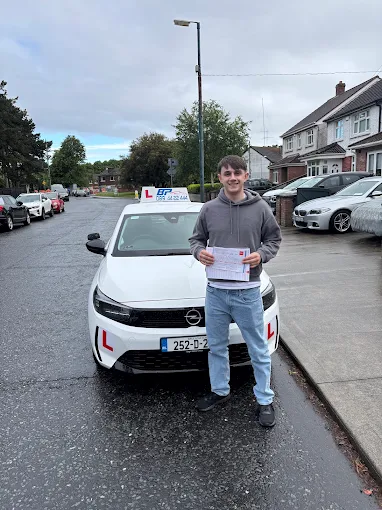 Student holding RSA driving test pass certificate next to BP Driving School Opel Corsa