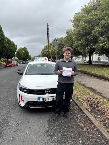 Student holding RSA driving test pass certificate next to BP Driving School Opel Corsa